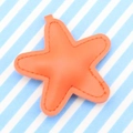 Orange starfish-shaped PU leather keychain with visible stitching on a striped background - Orange