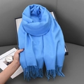 Soft blue winter scarf with fringe details held over a grey sofa background - 68x180cm / Lake Blue