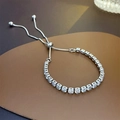 Detalle de pulsera plateada ajustable con circonitas cuadradas sobre fondo de cuero - Pulsera de piedras preciosas de cristal de plata