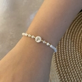 Detail of beaded shell bracelet with gold-tone letter P charm on a woman's wrist - Letter P Style (P)