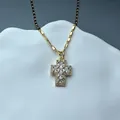 Detailed macro view of a gold cross pendant necklace featuring shimmering clear zircon stones - White Zircon Cross