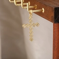 Dettaglio di un ciondolo a croce dorata con zirconi su un supporto espositivo in legno - Stile Croce 23