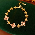 Detail eines Vintage-Goldarmbands mit orangefarbenen Zirkonia auf grünem Samt - Gold-Orange