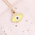 Macro shot of gold evil eye pendant with yellow enamel and black gemstone on stone surface - Yellow