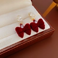 Dettaglio orecchini a fiocco in velluto rosso con metallo dorato e gemme in una scatola - Orecchini a Bottone con Fiocco in Velluto Rosso e Zirconia