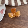 Elegant amber acetate bow hair claw clip with glossy finish and French style branding - Caramel