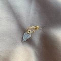 Macro shot of gold twist hoop earring with sparkling heart pendant on silk background - Gold