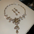 Set di gioielli floreali con cristalli champagne su una superficie di lussuosa pelle bianca - Set Argento-Marrone