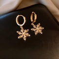 Close-up of golden snowflake earrings featuring sparkling zircons on a black leather base - Gold Hexagonal Snowflake Zirconia Huggie Earrings (24# Silver Pin-Gold Plated)