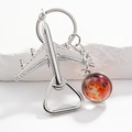 Close-up of silver airplane bottle opener keychain with red planet charm on stone - Red Moon Galaxy