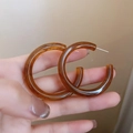 Handheld shot of amber resin C-shaped hoop earrings featuring a French retro design - 41# Silver Pin Brown C-Shape