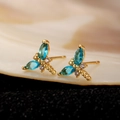 Makroaufnahme goldener Schmetterlings-Ohrclips mit blauen Markis-Steinen und Zirkonia - Goldene Libelle Ohrstecker