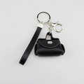 Detail van een zwarte PU-lederen mini-tas sleutelhanger met metalen sluiting en riem. - Zwart
