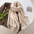 Detailed close-up of beige pashmina scarf with fringe edge and brand tag on a table - Off White
