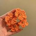 Detailed close-up of orange handmade woven flower earrings with gold bead centers - Silver Earring Post / Orange