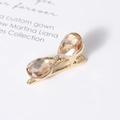 Detail view of crystal bow hair clip with champagne teardrop stones on gold metal base - Champagne