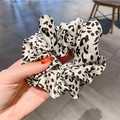 Detailed close-up of a white and black leopard print scrunchie held by a hand - White Leopard