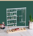 Close-up of metal jewelry stand with necklace hooks and wooden base on a table - White