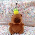 Plush brown capybara keychain with yellow pineapple hat on colorful foam background - Dark Brown Pineapple + Silver Clip