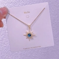 Dettaglio della collana a stella con gemma blu scuro e catena a croce dorata - Raggio di Sole Ottagramma (XK0040)