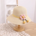 Détail d'un chapeau de paille pour enfant avec une fleur rose et un tissage artisanal - Chapeau Beige