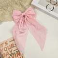 Macro shot of pink satin large bow hair clip with long ribbons on lace background - Pink
