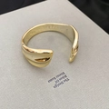 Dettaglio macro di un bracciale aperto dorato a onde con finitura metallica lucida - Onda Irregolare Oro (5# Bracciale)