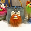 Dettaglio di portachiavi mostro in peluche colorati con fiocchi su borsa - Arancione