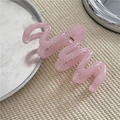 Detailed close-up of a pink wave-shaped matte hair claw clip on a textured surface - Transparent Pink