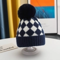 Gros plan du bonnet d'hiver en tricot bleu marine avec motif à carreaux et pompon doux - Bonnet à revers avec pompon / Bleu marine