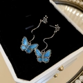 Detailed macro view of dark blue butterfly tassel earrings in a white velvet jewelry box - Silver Pin - Blue Butterfly Drop Earrings