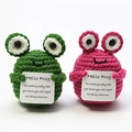 Detail of handmade crochet frog plushies in green and pink holding encouragement cards - Frog Couple