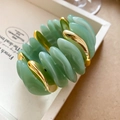 Makroaufnahme von mintgrünen Acrylperlen und goldenen Metallteilen auf einem elastischen Armband - Armband-Grün