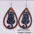 Macro shot of wooden teardrop earrings with a black cat silhouette, stars and moon design - Starry Night Cat