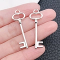 Detailed view of two vintage silver skeleton key pendants held in hand for size scaling - Key Shape (8464)