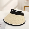 Beige straw visor hat with black fabric band shown on white table in a sunny room - Beige