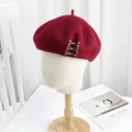 Elegant wine red wool beret featuring antique bronze metal buckles on a mannequin - M (56-58cm) / Gold Buckle - Wine Red