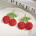 Detalle de pendientes de cereza tejidos a mano con bayas rojas y hojas verdes en oro - Rojo