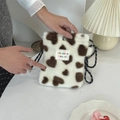 Close-up of heart pattern plush crossbody bag held by hand in a cozy interior setting - White Hearts