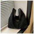 Detalle de bolso tote de ante negro con correa de cuero junto a ventana con luz natural - Negro