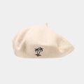 Detailed close-up of beige wool beret featuring black coconut tree embroidery detail - Beige