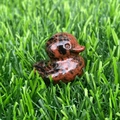 Crystal duck figurine carved from red and black spotted natural stone on green grass - Mahogany Obsidian