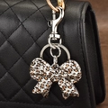 Bow-shaped metal keychain with leopard print enamel on a black quilted leather bag - Leopard Bow