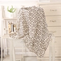 Close-up detail of leopard print muslin cotton baby blanket draped over a vintage wood table - Leopard Print