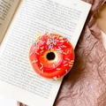 Single 3D donut phone grip with red icing and colorful sprinkles on book background - Donut Holder-Red