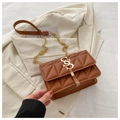 Brown quilted crossbody bag with gold S-logo and chain strap on a blazer background - Brown