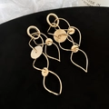 Makroaufnahme goldener geometrischer Quastenohrringe mit Ausschnitten auf Samt - Silbernadel / Gold