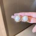 French vintage style gold earrings with white textured resin inlays shown by hand - White Pearl