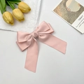 Close-up of a large pink silk satin bow hair clip styled with yellow tulips and a card - Pink
