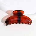 Vue détaillée d'une pince à cheveux ambre semi-circulaire au fini brillant - Ambre